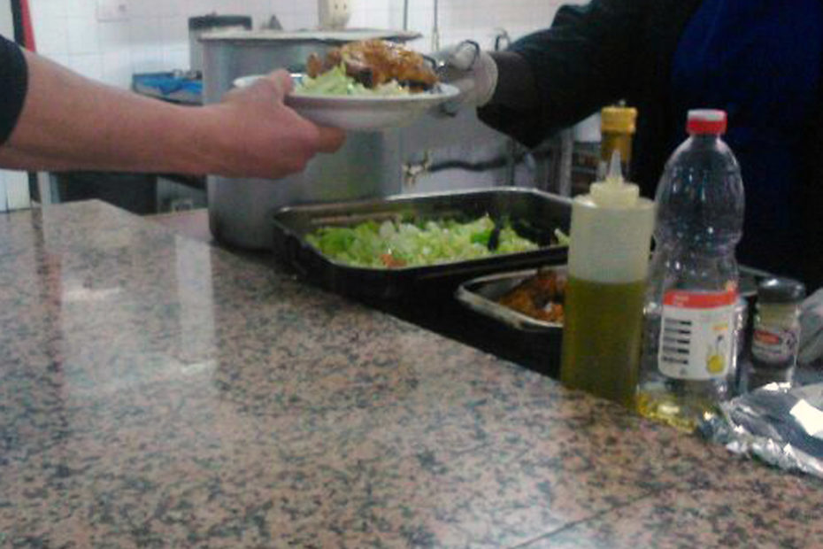 Cuinera servint un plat de menjar a un usuari.