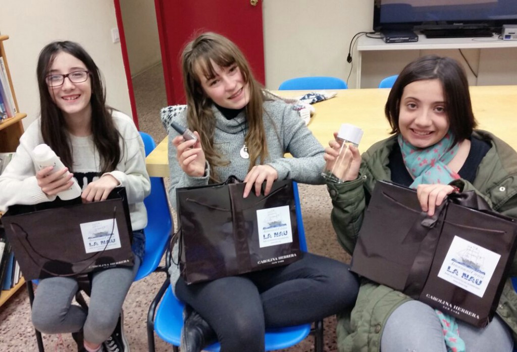 Tres nenes obrint el kit d’higiene que l'associació La Nau els va regalar per Reis.
