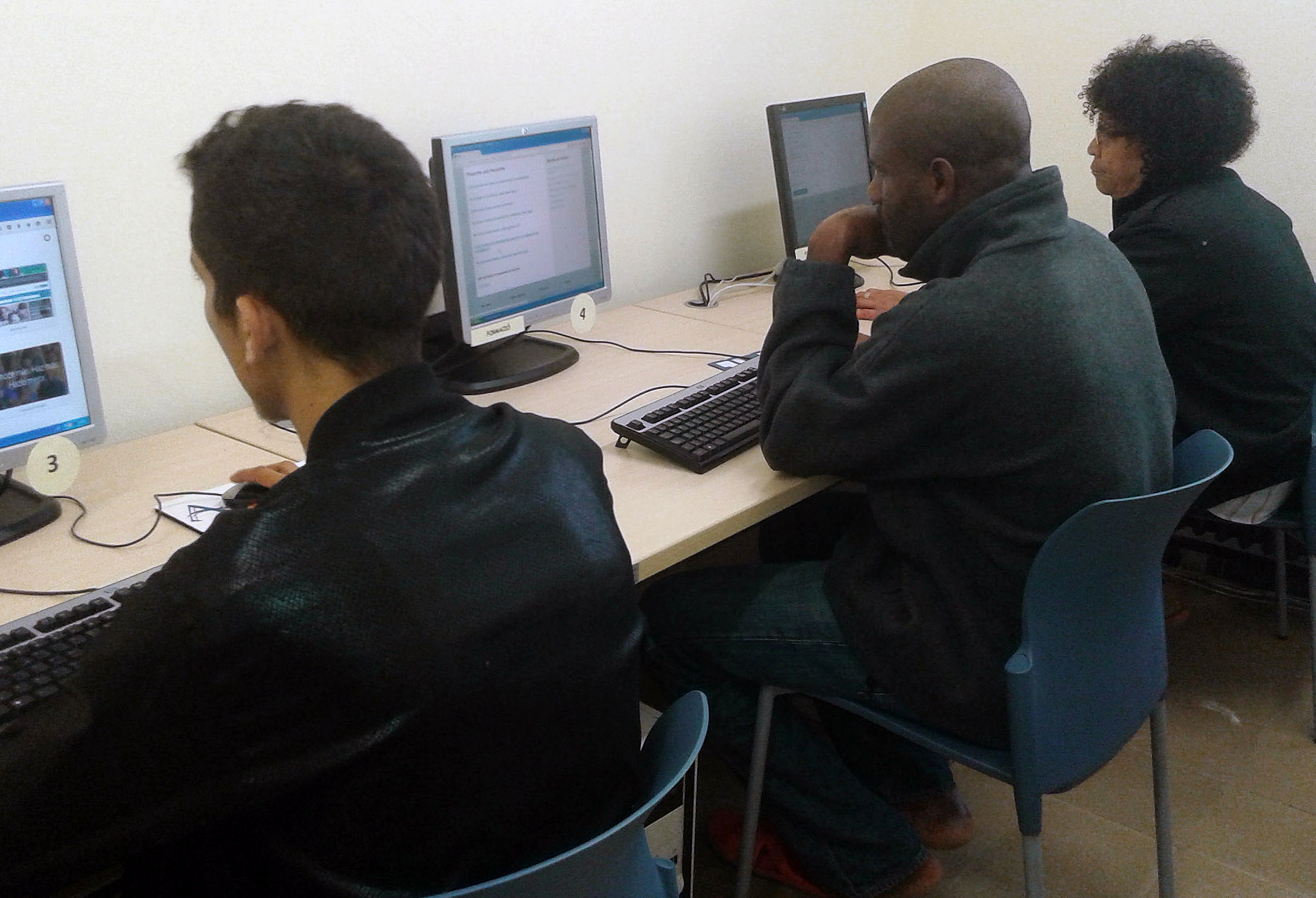 Tres participants del taller d'inserció laboral utilitzant ordinadors